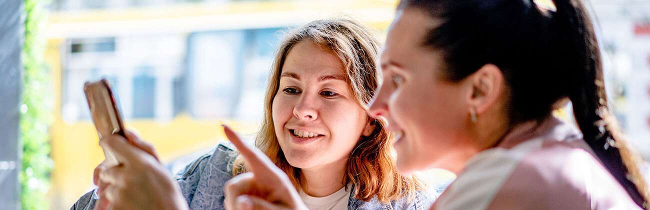 Women look at phone in a cafe