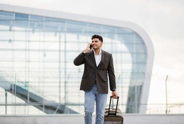 Man outside airport uses mobile phone while traveling